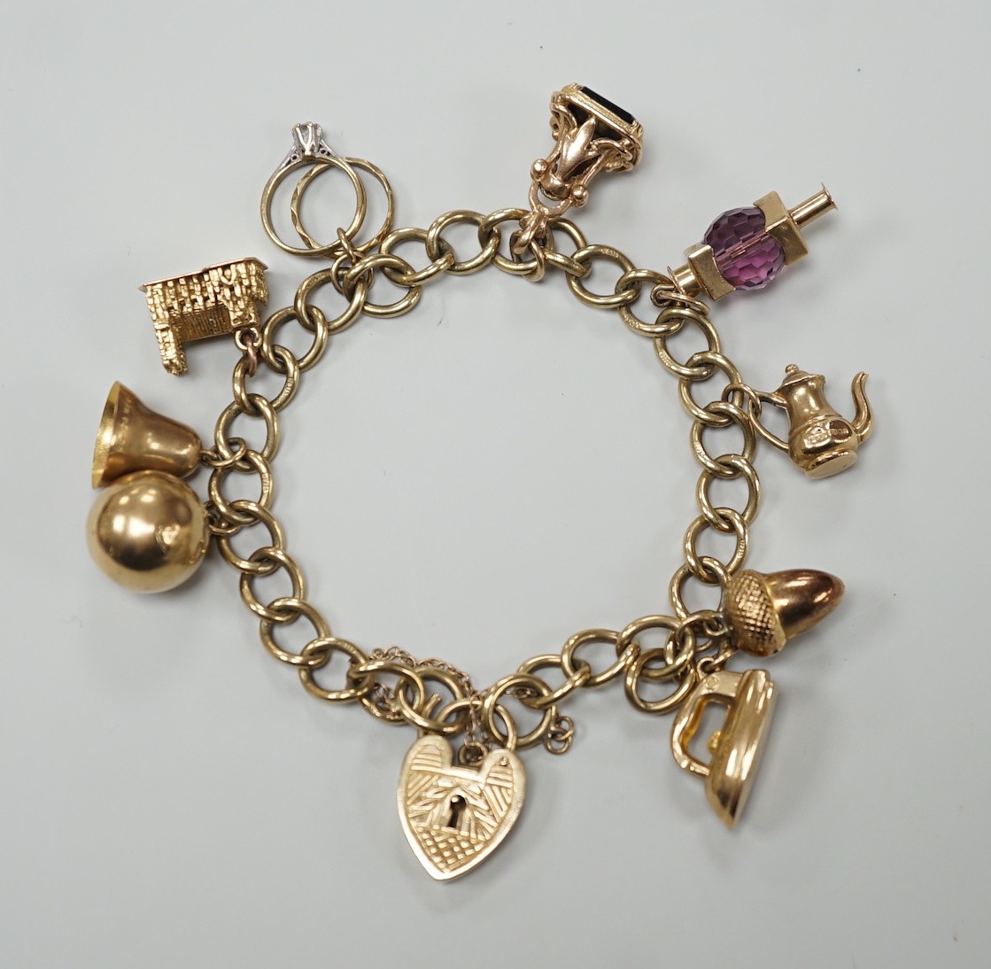 A 9ct gold oval link charm bracelet, hung with ten assorted charms including nine 9ct gold, gross weight 31.9 grams.